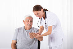 年轻女医生临床检查老年男性患者脉搏