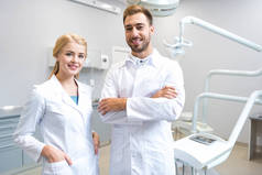 年轻的男性和女性牙医看相机在牙科诊所