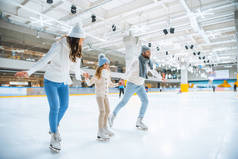 微笑的家庭手牵手, 而一起在溜冰场上溜冰