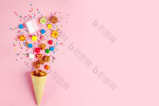华夫角与彩色糖果, 糖果, 棉花糖, 焦糖爆米花, 粉红色背景上的甜粉。顶级视野、糖果和糖果概念