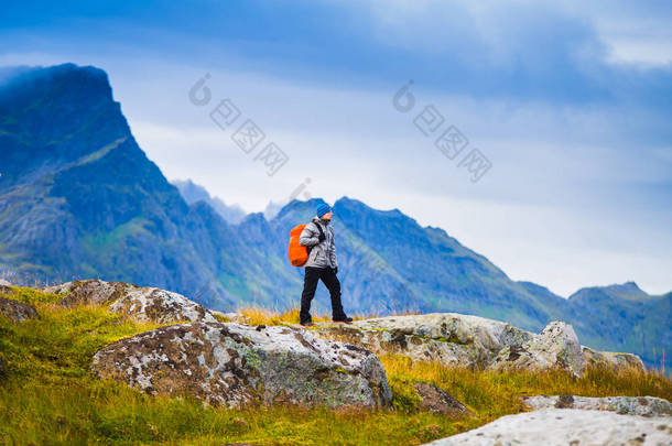 在挪威徒步旅行。徒步者与红色背包站立在山<strong>的</strong>背景。<strong>人与自然的</strong>概念.