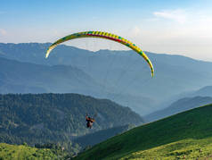 绿山上蓝色晴朗天空中的滑翔伞