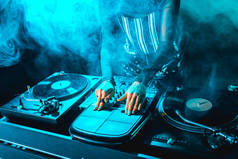 裁剪视图的 dj 妇女使用 dj 设备在夜总会与烟雾