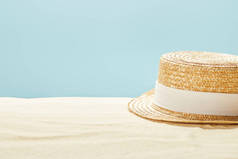 在夏季孤立在蓝色沙滩上的草帽选择性焦点