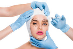 穿着蓝色乳胶手套的整形外科医生的裁剪视图, 用注射器靠近妇女的脸, 在白色上查出痕迹