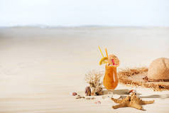 鸡尾酒，海星，草帽，珊瑚和海石在沙滩上与复制空间