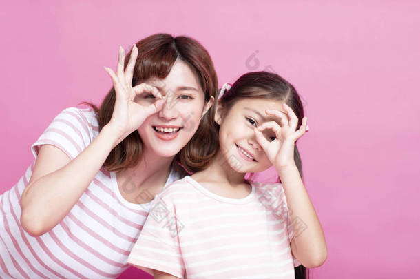 幸福的母亲和女儿牵着手指靠近眼睛
