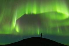 人剪影上方的绿色北极光的风景