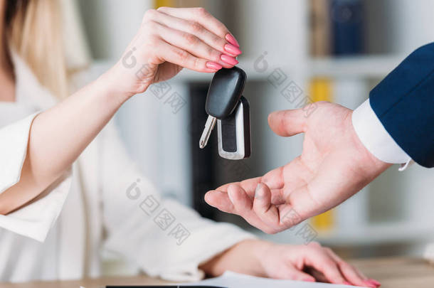 裁剪镜头的女人从汽车经销商在办公室采取汽车钥匙