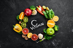 含有维生素C的水果和蔬菜：橙子、柠檬、苹果、玫瑰、大蒜、花椰菜、苹果、奇异果、菠菜。顶部视图。在黑色的石头背景上.