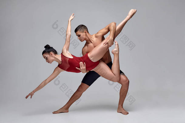 一对现代芭蕾舞演员的情侣在灰色的演播室背景下摆姿势.