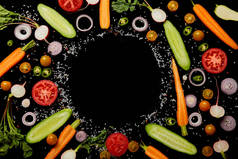 新鲜蔬菜片的顶部视图与盐与空的圆形框架隔离在黑色