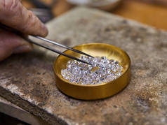 珠宝生产。在钻石背景下由钳子持有的钻石