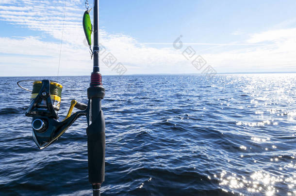 钓鱼杆旋转环与线特写。钓鱼竿在水晶静水中。钓鱼竿环。渔具。钓鱼纺纱卷轴。柔和的照明