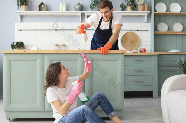 Young happy couple is having fun while doing cleaning at home.