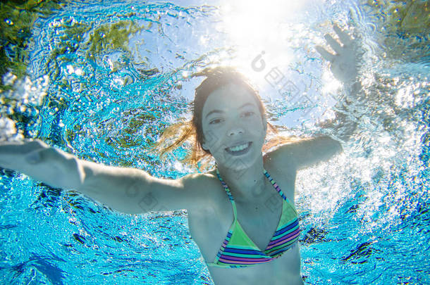 Child swims underwater in swimming pool, <strong>happy</strong> active teenager girl dives and has fun under water, k