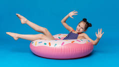 快乐的小女孩游泳在甜甜圈形状的粉红色充气环
