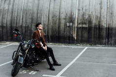 全长视图的帅哥在夹克休息黑色摩托车和看远