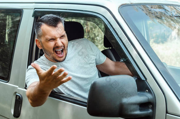 咄咄逼人的人,汽车的司机在旅途中对车轮感到愤怒。紧急情况,事故,侵犯权利,纠纷,坏司机