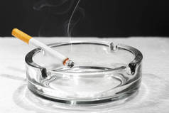 桌子上透明烟灰缸上的香烟