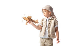 梦幻般的探险家男孩在眼镜和帽子拿着木制玩具飞机孤立在白色
