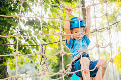 夏天阳光明媚,可爱的小男孩在攀岩探险公园里享受活动。攀岩极限运动与头盔和保险
