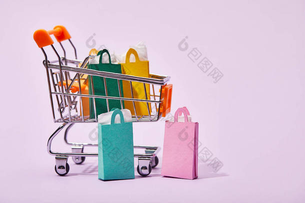 玩具车与五颜六色的纸袋近几个购物袋在紫色背景