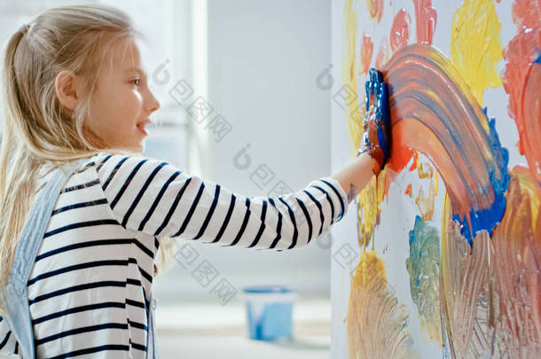 快乐的小女孩,双手浸在生动的油漆画在墙上五颜六色的抽象。她有乐趣和笑。家正在装修.