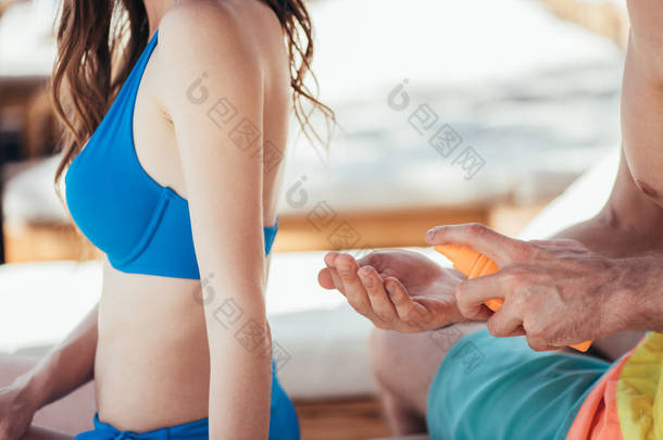 男人拿着一瓶防晒霜化妆水靠近女友
