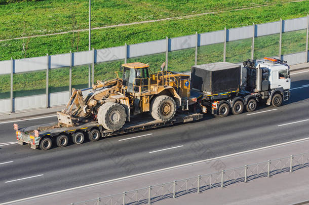 卡车有一个长拖车平台,用于运输<strong>重型机械</strong>,装载大型拖拉机与桶。公路运输.