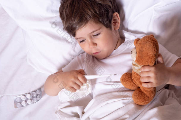 患病儿童发烧和生病在床上检查体温与温度计。儿童流感治疗.