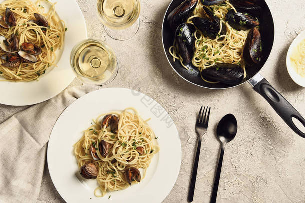 美味的意大利面与海鲜的顶视图，在纹理灰色表面提供白葡萄酒和餐巾纸