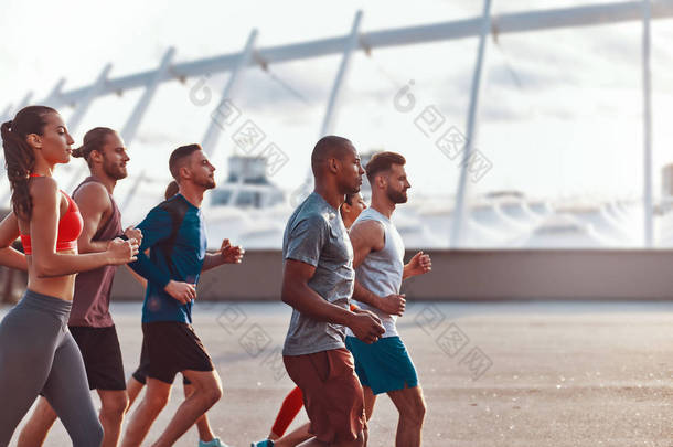 一群穿着运动服的年轻人在<strong>奥林匹克体育</strong>场大楼的城市慢跑