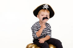 Happy child on Halloween. Funny little boy in carnival costumes of pirates holds an artificial black