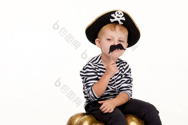 Happy child on Halloween. Funny little boy in carnival costumes of pirates holds an artificial black