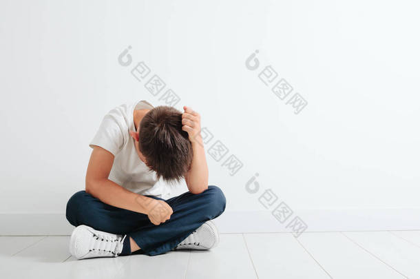 一个抑郁的孩子<strong>坐在地板上</strong>