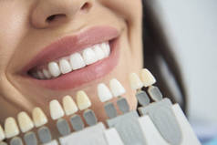 人造牙齿定位在微笑的女性嘴唇附近