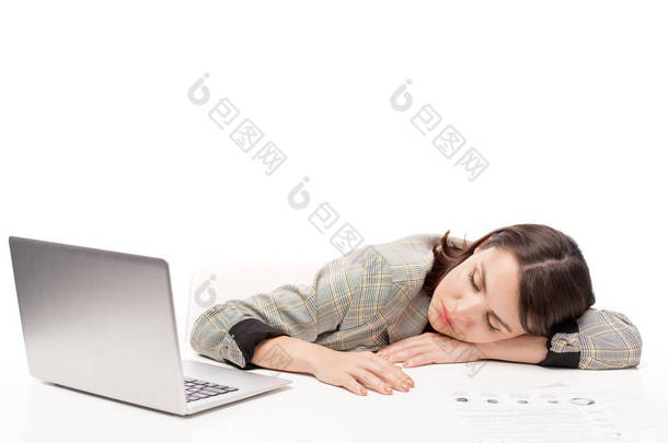 年轻过度劳累的女学生或办公室工作人员在准备考试或项目时睡在笔记本电脑前的办公桌上