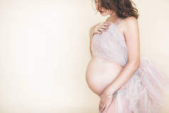 美丽的孕妇在中性背景。期待特写图片。未来母亲肖像在柔和的背景.
