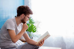 年轻人戴眼镜在客厅的房间里看书