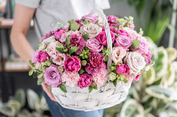 威克篮子中的花布置。美丽的花束混合花在女人的手。花卉店概念。漂亮的新鲜花束。鲜花递送