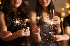 快乐的女人与圣诞火花和香槟酒杯在党