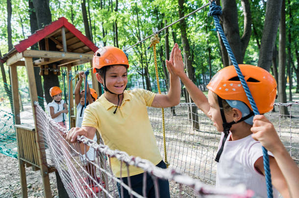 selective focus of happy boy giving high five to friend in helmet