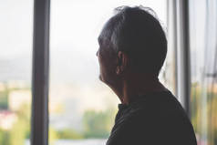 一个老人在窗户背景的剪影。老年。抑郁症领取者。退休孤独.