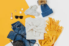 蓝色冬帽，白色背景有牛仔裤、毛衣、手袋和黄色围巾。女士时尚的秋冬套装。时髦的服装拼贴画。平铺，顶视图.
