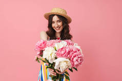 快乐快乐微笑的年轻可爱的女人摆出孤立的粉红色墙壁背景拿着花.
