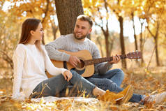 秋日公园里带着吉他的年轻夫妇