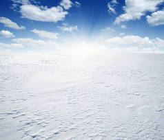 天空和阳光下白雪覆盖的田野.