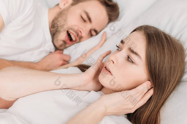 卧床靠近打鼾丈夫时，妇女用手塞住耳朵的<strong>选择性</strong>焦点