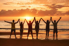 快乐的朋友一起举手表决夕阳西下的大海
